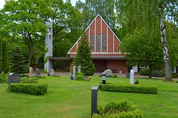 Außenansicht der Kapelle auf dem Südfriedhof Trittau mit Rasenflächen, Bäumen und Grabsteinen im Vordergrund.